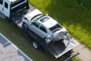 A totaled leased car on the back of a tow truck.