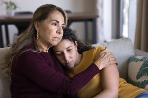 A mother consoling her daughter, wondering, “What rights do child sexual abuse survivors and their families have?”